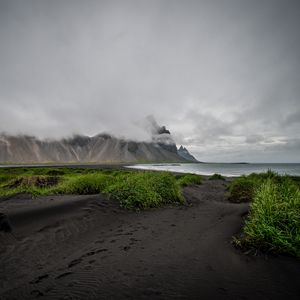 Preview wallpaper grass, coast, sea, mountains, clouds