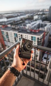 Preview wallpaper hand, camera, city, buildings, roofs