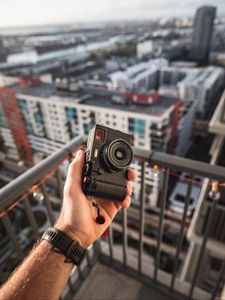 Preview wallpaper hand, camera, city, buildings, roofs