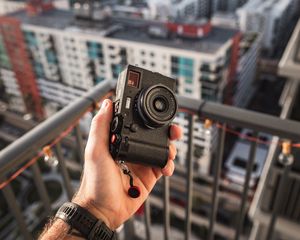 Preview wallpaper hand, camera, city, buildings, roofs