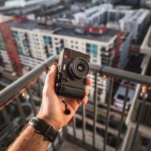 Preview wallpaper hand, camera, city, buildings, roofs