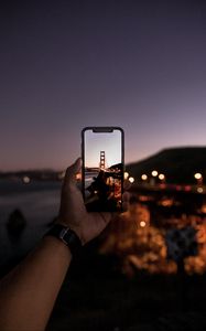 Preview wallpaper hand, phone, photo, bridge, sunset, lights