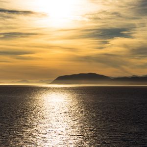Preview wallpaper hill, sunset, clouds, sea, glare