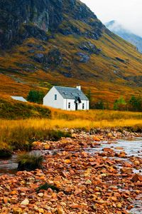 Preview wallpaper house, lake, stones, grass, mountains