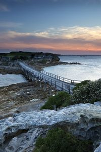 Preview wallpaper island, bridge, sea, stones, dusk