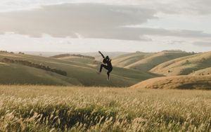 Preview wallpaper jump, levitation, silhouette, field, hills