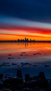 Preview wallpaper lake, shore, city, buildings, sunset, dusk, dark