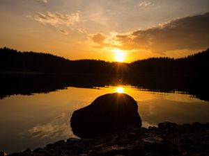 Preview wallpaper lake, stone, sunset, reflection, sun, sky, forest, coast