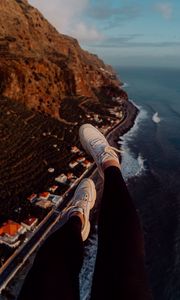 Preview wallpaper legs, sneakers, city, aerial view, coast, mountains