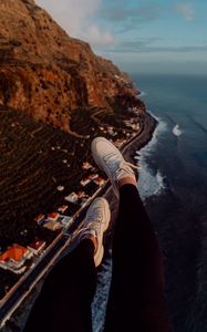 Preview wallpaper legs, sneakers, city, aerial view, coast, mountains