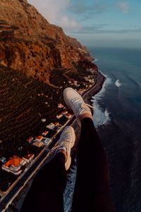 Preview wallpaper legs, sneakers, city, aerial view, coast, mountains