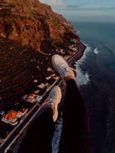 Preview wallpaper legs, sneakers, city, aerial view, coast, mountains