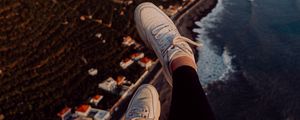 Preview wallpaper legs, sneakers, city, aerial view, coast, mountains