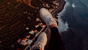 Preview wallpaper legs, sneakers, city, aerial view, coast, mountains