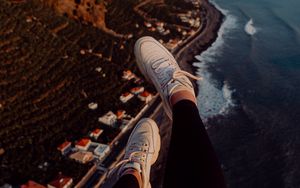 Preview wallpaper legs, sneakers, city, aerial view, coast, mountains