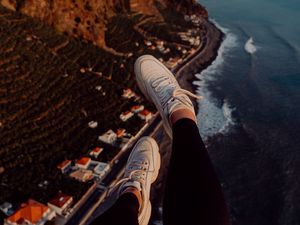 Preview wallpaper legs, sneakers, city, aerial view, coast, mountains