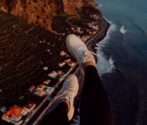 Preview wallpaper legs, sneakers, city, aerial view, coast, mountains