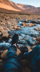 Preview wallpaper legs, sneakers, coast, stones, mountains