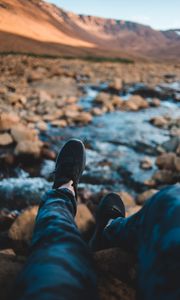 Preview wallpaper legs, sneakers, coast, stones, mountains