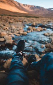 Preview wallpaper legs, sneakers, coast, stones, mountains