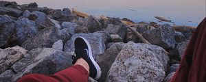 Preview wallpaper legs, sneakers, rocks, city, horizon, sea