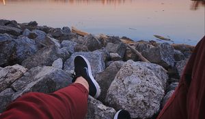 Preview wallpaper legs, sneakers, rocks, city, horizon, sea