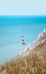 Preview wallpaper lighthouse, building, boat, sea, grass, horizon