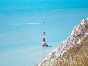 Preview wallpaper lighthouse, building, boat, sea, grass, horizon