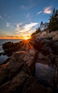 Preview wallpaper lighthouse, buildings, rocks, rays, sea