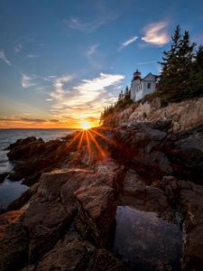 Preview wallpaper lighthouse, buildings, rocks, rays, sea