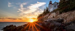 Preview wallpaper lighthouse, buildings, rocks, rays, sea