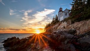 Preview wallpaper lighthouse, buildings, rocks, rays, sea