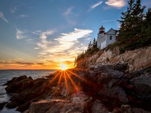 Preview wallpaper lighthouse, buildings, rocks, rays, sea