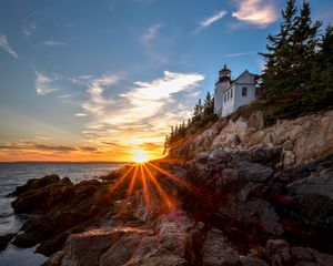 Preview wallpaper lighthouse, buildings, rocks, rays, sea
