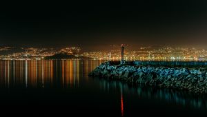 Preview wallpaper lighthouse, city, water, night, stones