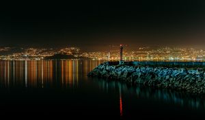 Preview wallpaper lighthouse, city, water, night, stones