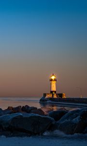 Preview wallpaper lighthouse, fire, stones, sea, twilight