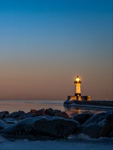 Preview wallpaper lighthouse, fire, stones, sea, twilight