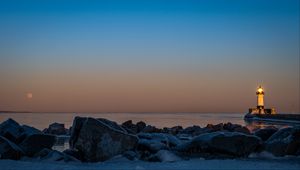 Preview wallpaper lighthouse, fire, stones, sea, twilight