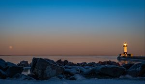 Preview wallpaper lighthouse, fire, stones, sea, twilight