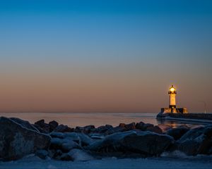 Preview wallpaper lighthouse, fire, stones, sea, twilight