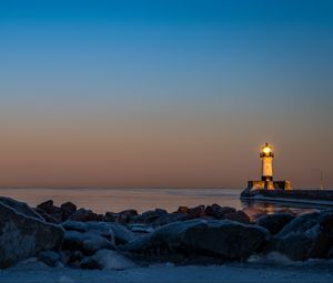 Preview wallpaper lighthouse, fire, stones, sea, twilight