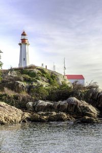 Preview wallpaper lighthouse, house, stones, shore, sea