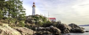 Preview wallpaper lighthouse, house, stones, shore, sea