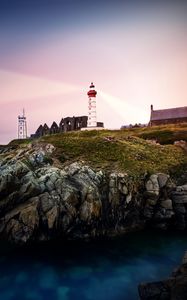 Preview wallpaper lighthouse, rock, cliff, sea, rays