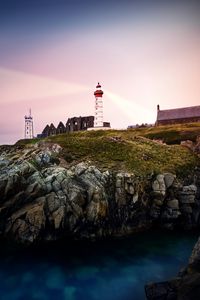 Preview wallpaper lighthouse, rock, cliff, sea, rays