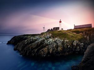 Preview wallpaper lighthouse, rock, cliff, sea, rays