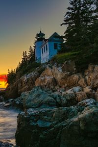 Preview wallpaper lighthouse, rocks, cliff, sea, sunset
