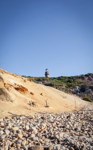 Preview wallpaper lighthouse, stones, slope, sky