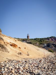 Preview wallpaper lighthouse, stones, slope, sky